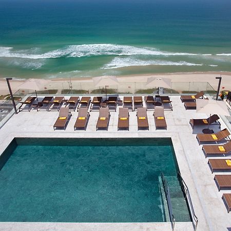 Windsor Marapendi Hotel Rio de Janeiro Ngoại thất bức ảnh The photo shows a rooftop area with a swimming pool and several lounge chairs arranged around it. The pool has a clear blue surface, and the lounge chairs are positioned in a neat row, some with yellow cushions. In the background, you can see a beaut